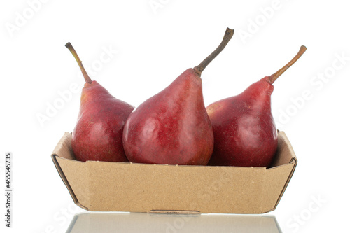 Three ripe red pears in a paper bowl, close-up, isolated on white.