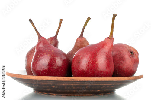 Several ripe red pears on a clay dish, close-up, isolated on white.