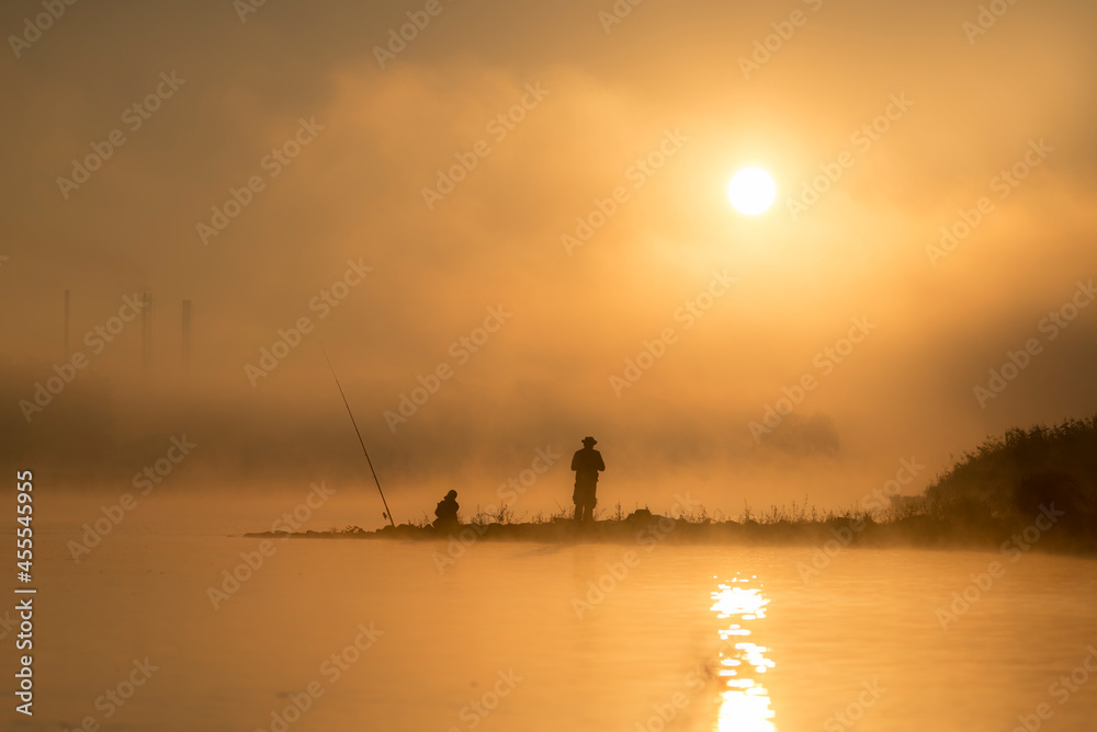 Wędkarze łowią ryby o wschodzie słońca nad rzeką