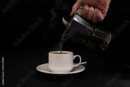 Moka coffee maker on black background and a mug