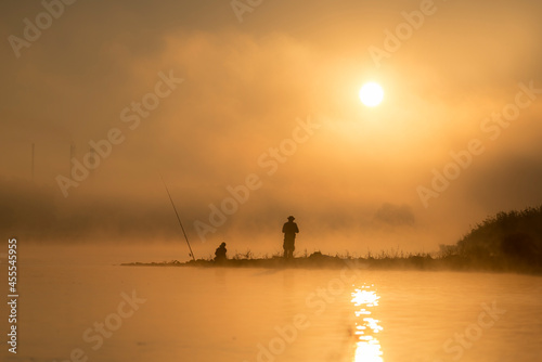 Wędkarze łowią ryby o wschodzie słońca nad rzeką © M