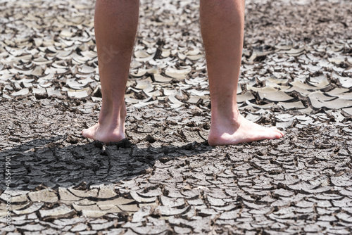 bare feet of a person on dry soil without plants close up © Sofiia
