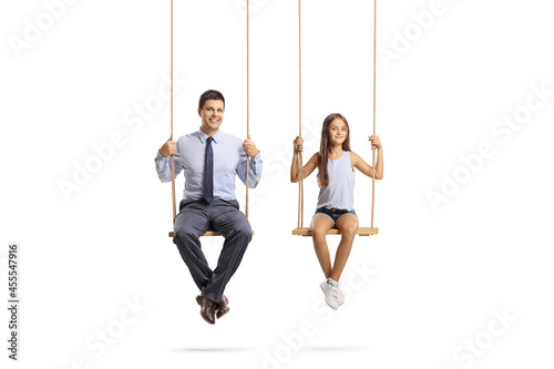 Father and daughter sitting on wooden swings and looking at camera