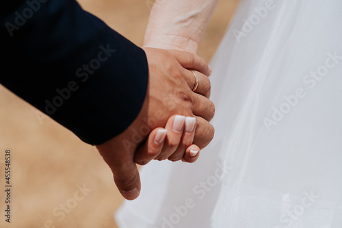 Close-up unrecognizable bride and groom holding hands