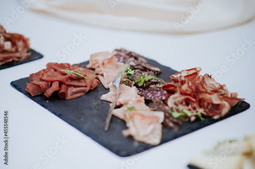 Platter of cold cuts on black stone plate.