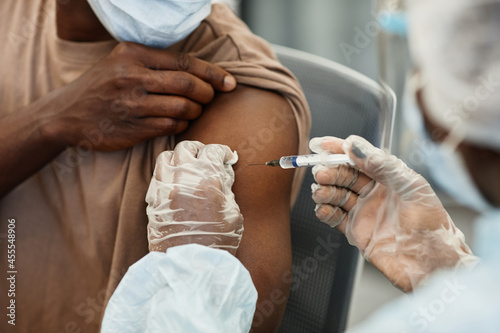 Close-up image of nurse in protective gloves giving shot of vaccine against covid-19 to patient in medical mask