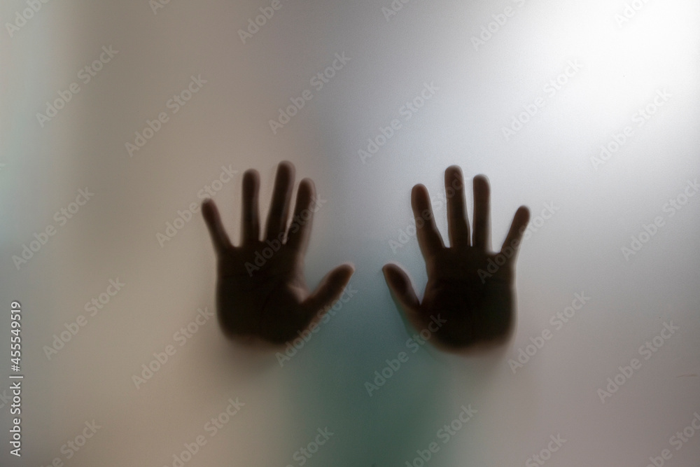 Silhouette of two blurred hands behind the frosted glass. Concept of asking for help and domestic violence. Silhouette of two blurred hands behind the frosted glass. Concept of asking for help and domestic violence.