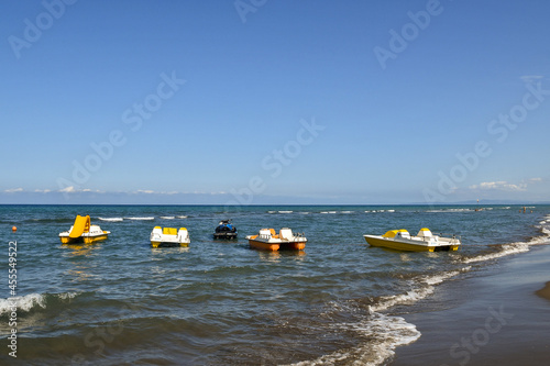 Seascape of the Maremma Tuscan coast with a row of pedalboats and a jet ski on the shore in summer, Marina di Castagneto Carducci, Livorno, Tuscany, Italy photo