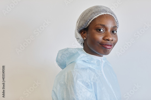 Portrait of beautiful sweaty young smiling medical nurse in PPE suit lookig at camera