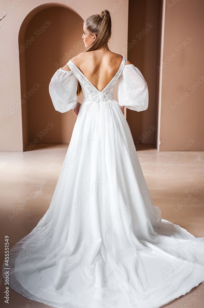 Fototapeta premium Perfect bride, portrait of a girl in a long white dress. Beautiful hair and clean delicate skin. Wedding hairstyle blonde woman. 