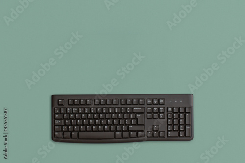 Computer black keyboard on green background. Top view. Flat lay. 