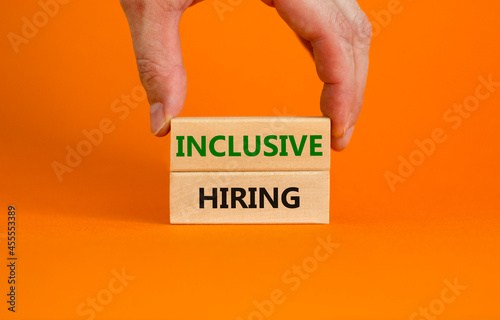 Inclusive hiring symbol. Wooden blocks with words Inclusive hiring on beautiful orange background. Businessman hand. Business, HR and inclusive hiring concept. Copy space.