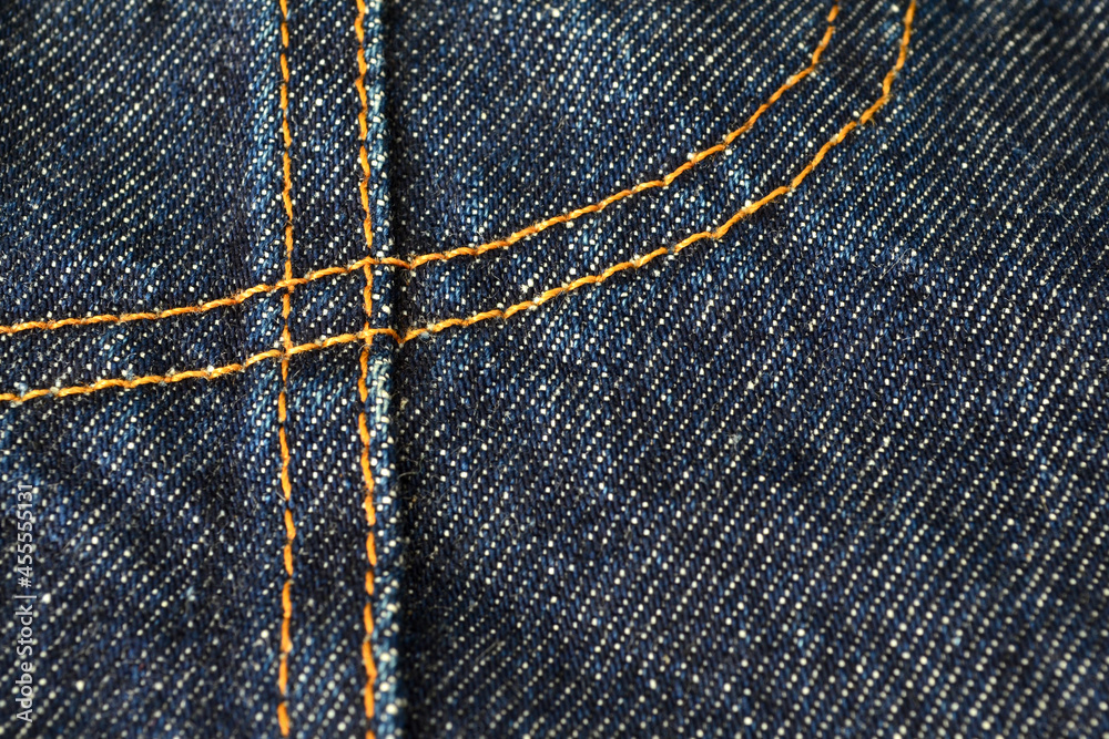 yellow sewing on blue jeans from close up yellow sewing on blue jeans from close up