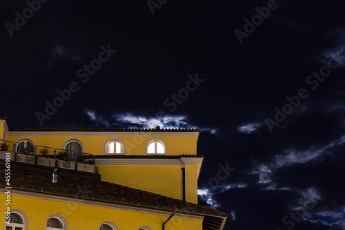 House facade in Riva del Gerda in front of a night sky partially illuminated by the moon
