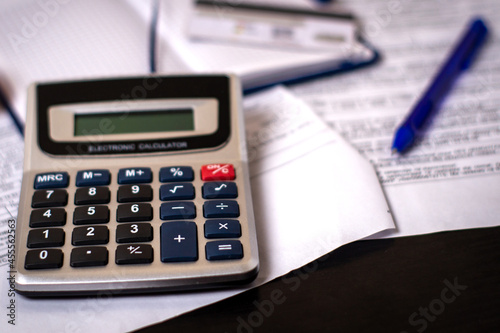 Calculator, pen, notepad and credit card on paper receipts. Payment for housing services, planning expenses and income.