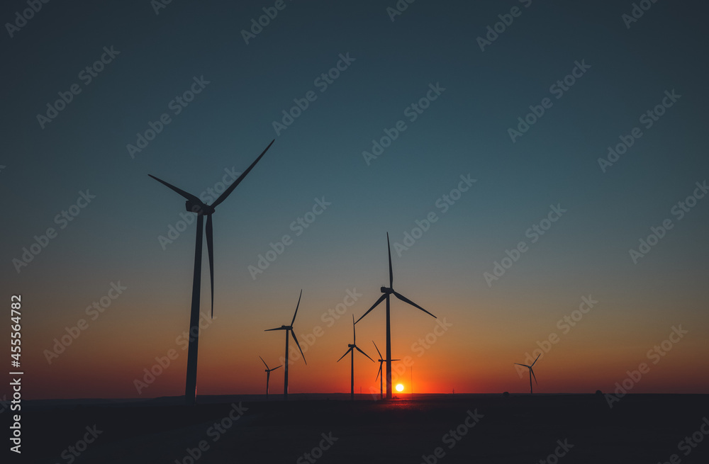 Wind Turbines produce energy n motion silhouette at sunset