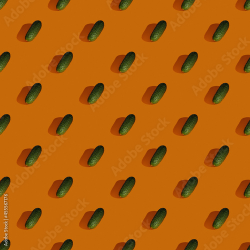 Seamless pattern made from green cucumber on orange background, Flat lay