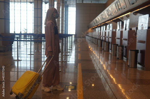 teenage girl with blonde hair standing near the information board to the airport