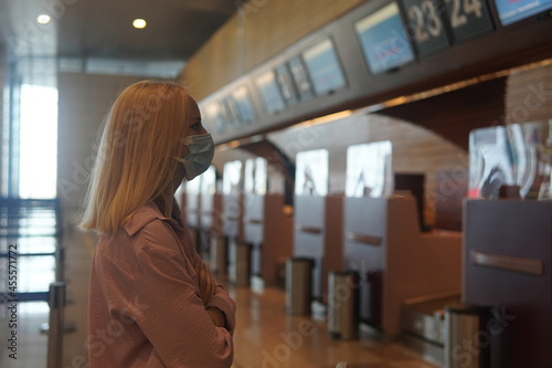 teenage girl with blonde hair standing near the information board to the airport