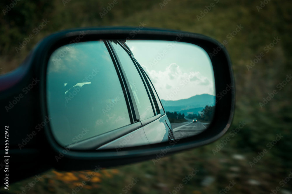 Blue reflection of a road and nature in a car mirror
