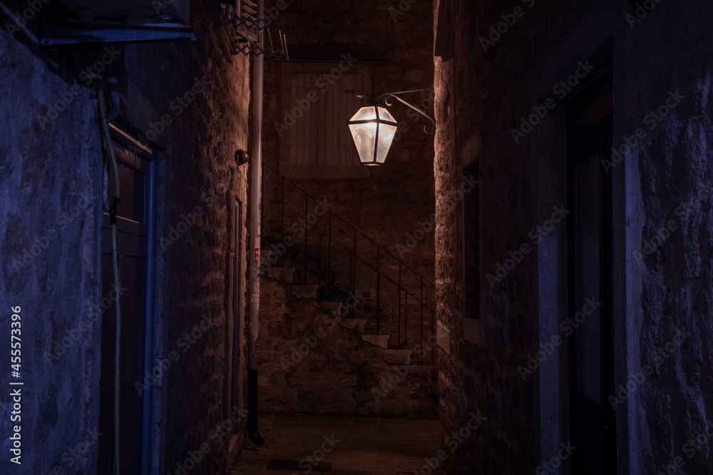 Medieval narrow orange lit alley at night in old town with a lantern Medieval narrow orange lit alley at night in old town with a lantern