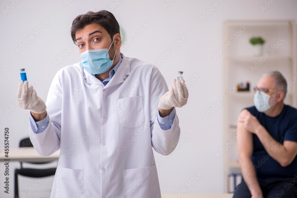 Old male patient visiting young male doctor in vaccination conce Old male patient visiting young male doctor in vaccination conce