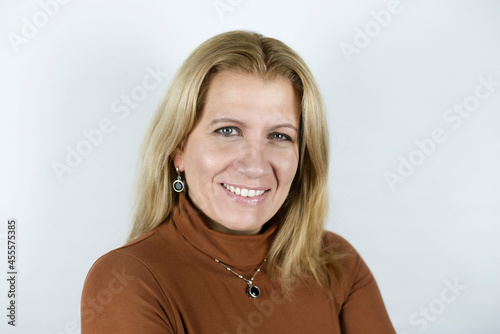 Portrait of a beautiful happy middle-aged woman on a light background, the concept of beauty and health after 45 years. The woman has an american smile, white teeth and blonde painted hair photo