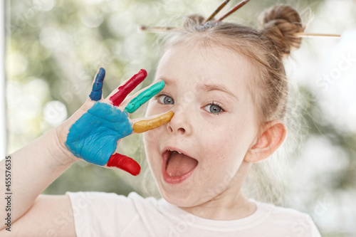 education, school, art and painitng concept - little student girl showing painted hands. High quality photo