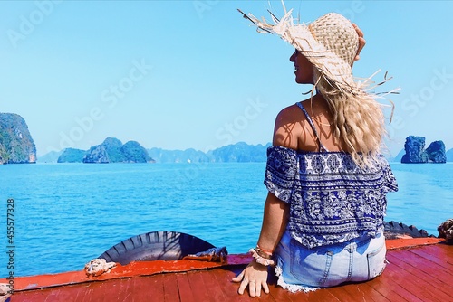 Back view of a woman sitting on wooden dock beside sea photo