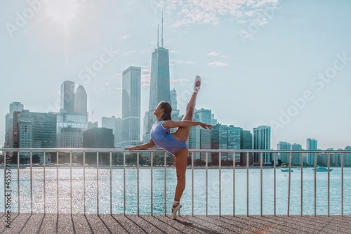 Ballerina doing a leg hold on pointe by the water in front of cityscape photo