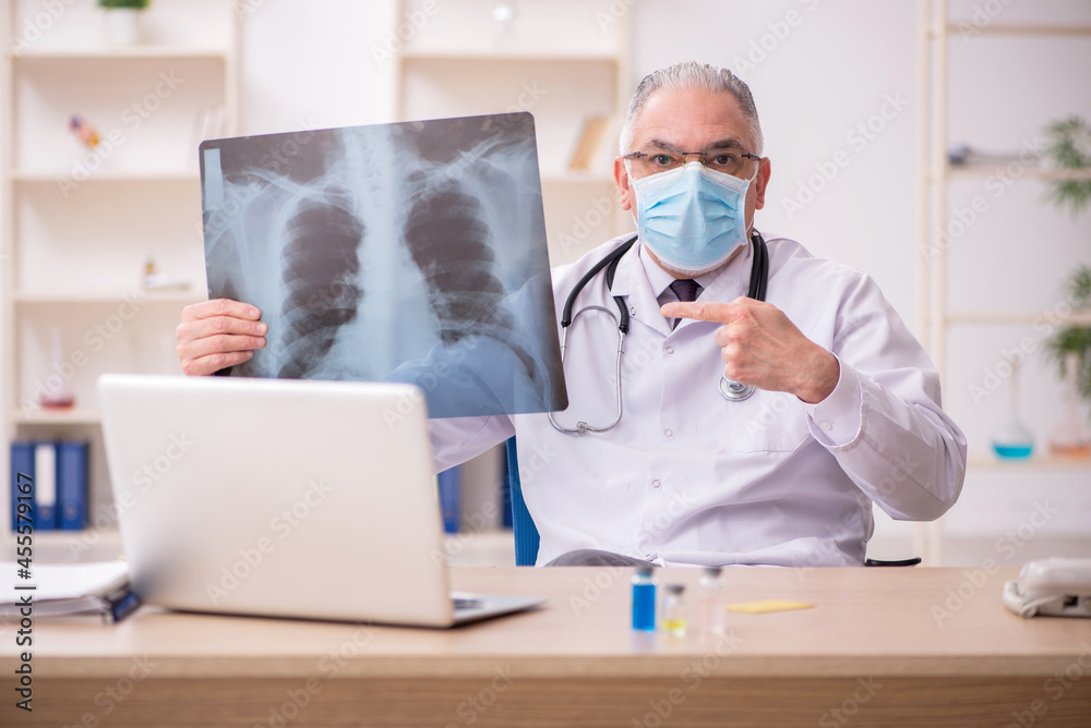 Old male doctor radiologist working in the clinic during pandemi Old male doctor radiologist working in the clinic during pandemi