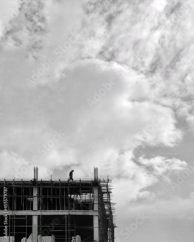 Grayscal photo of man standing on rooftop of construction site u photo