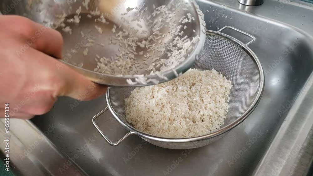 Home cooking - Draining washed white uncooked rice getting grain ready for cooking.