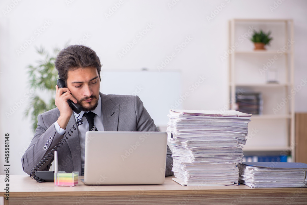 Young male employee and too much work in the office Young male employee and too much work in the office