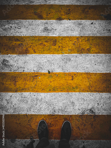 Person standing on yellow and white striped asphalt road photo