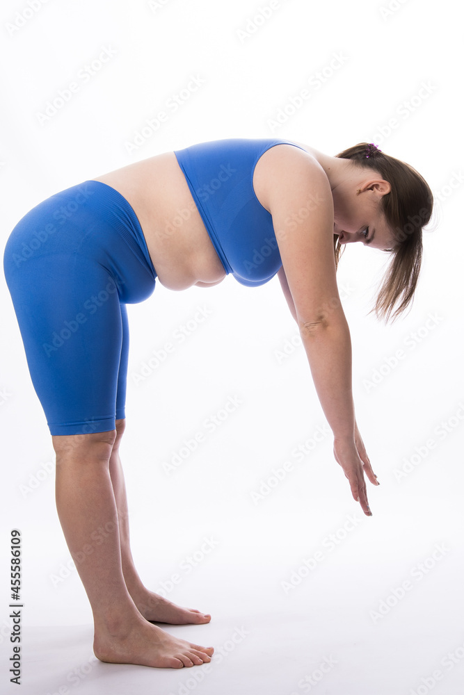 a girl of European appearance in a blue suit is engaged in fitness or yoga. White background. not a perfect figure. Sports training. bends with a straight back