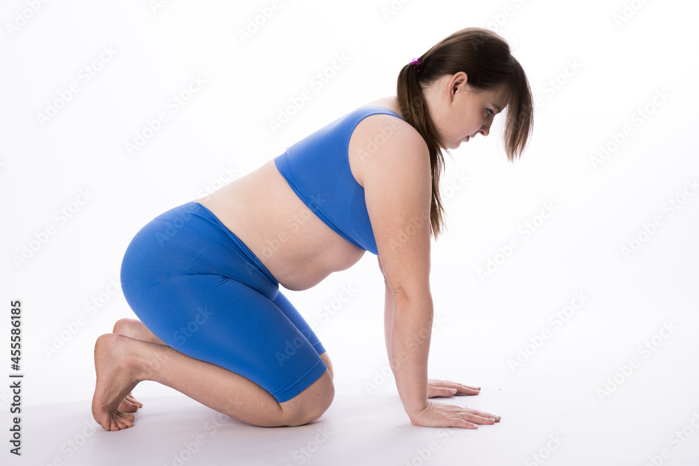 Fototapeta premium girl in a blue suit is engaged in fitness or yoga. White background. not a perfect figure. Sports training.