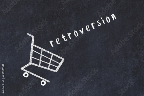 Chalk drawing of shopping cart and word retroversion on black chalboard. Concept of globalization and mass consuming photo