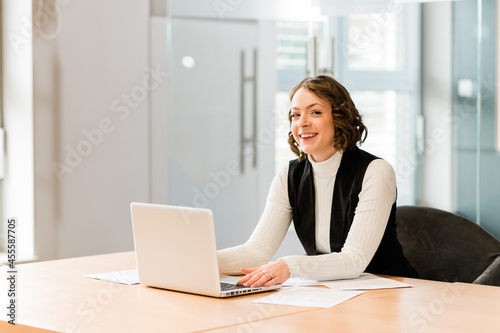 Woman in black cardigan sitting by the table using MacBook photo