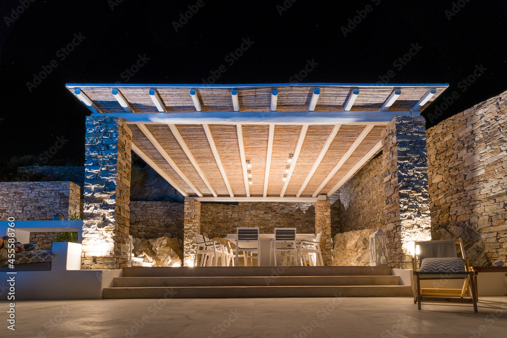 Trendy outdoor patio pergola shade structure, awning and patio roof, garden lounge and chairs. Night shot Trendy outdoor patio pergola shade structure, awning and patio roof, garden lounge and chairs. Night shot