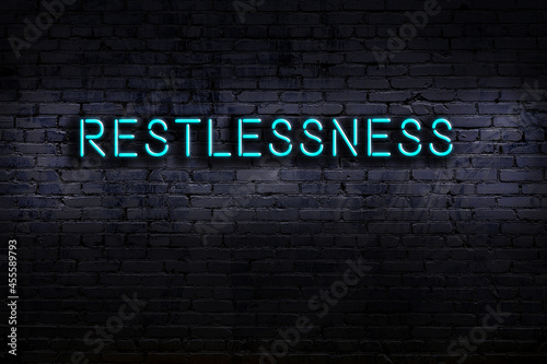 Night view of neon sign on brick wall with inscription restlessness photo