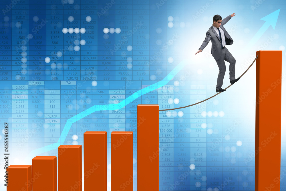 Businessman walking on tight rope between bar chart Businessman walking on tight rope between bar chart