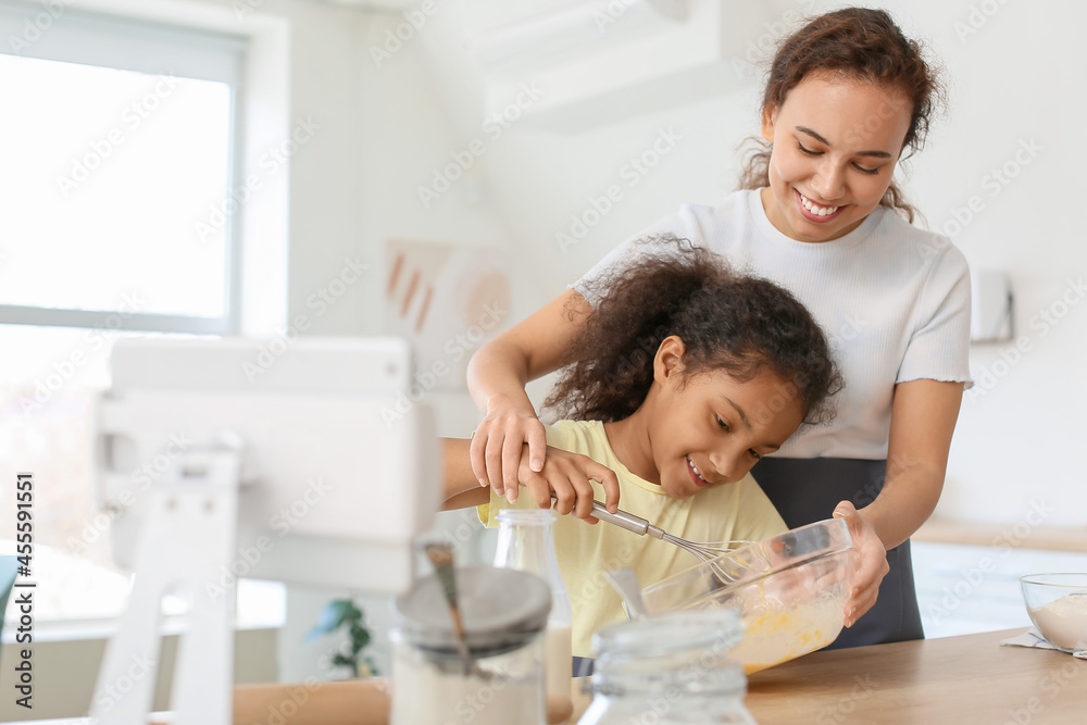 African-American little girl and her mother cooking in kitchen African-American little girl and her mother cooking in kitchen