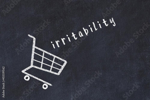 Chalk drawing of shopping cart and word irritability on black chalboard. Concept of globalization and mass consuming photo