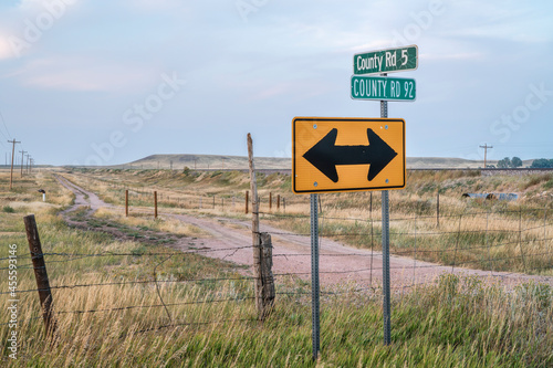 prairie landscape of rural northern Colorado with road signs, ranch road, barbed wire fences, railroad and power lines, late summer scenery with smoke and haze from distant wildfires