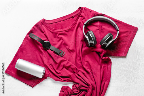 Composition with stylish t-shirt, headphones, wrist watch and soda on light background