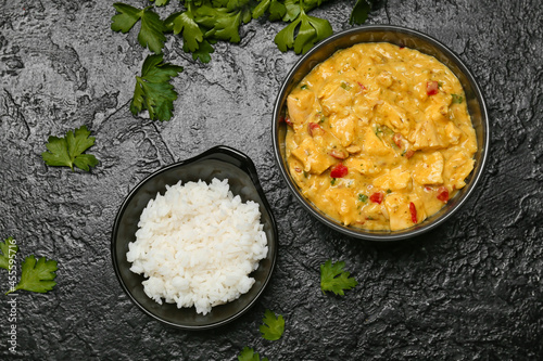 Bowl of tasty chicken curry with rice on dark background