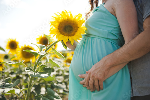 Pregnant woman with her husband in a field of sunflowers . Sunflower near pregnant belly photo