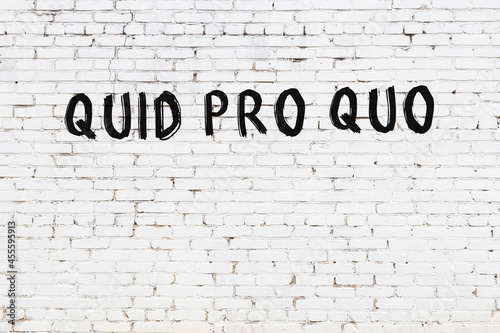 Inscription quid pro quo painted on white brick wall photo