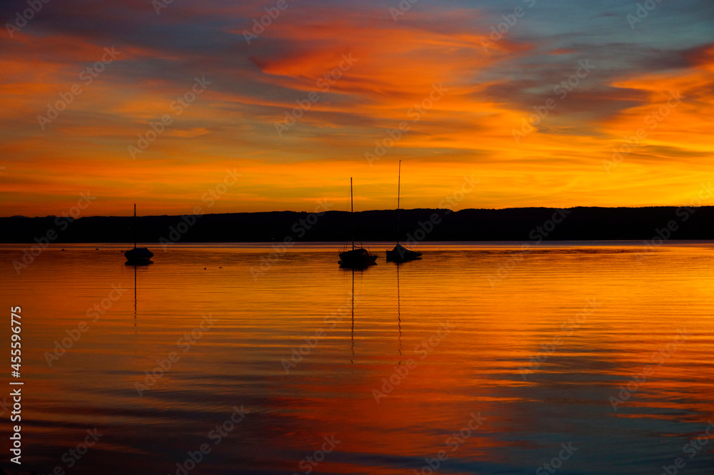 a breathtaking burning sunset on lake Ammersee with sailing boats resting on the water (Herrsching am Ammersee in Germany)